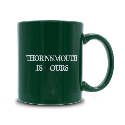 Green mug that reads thornsmouth is your's the Y is black